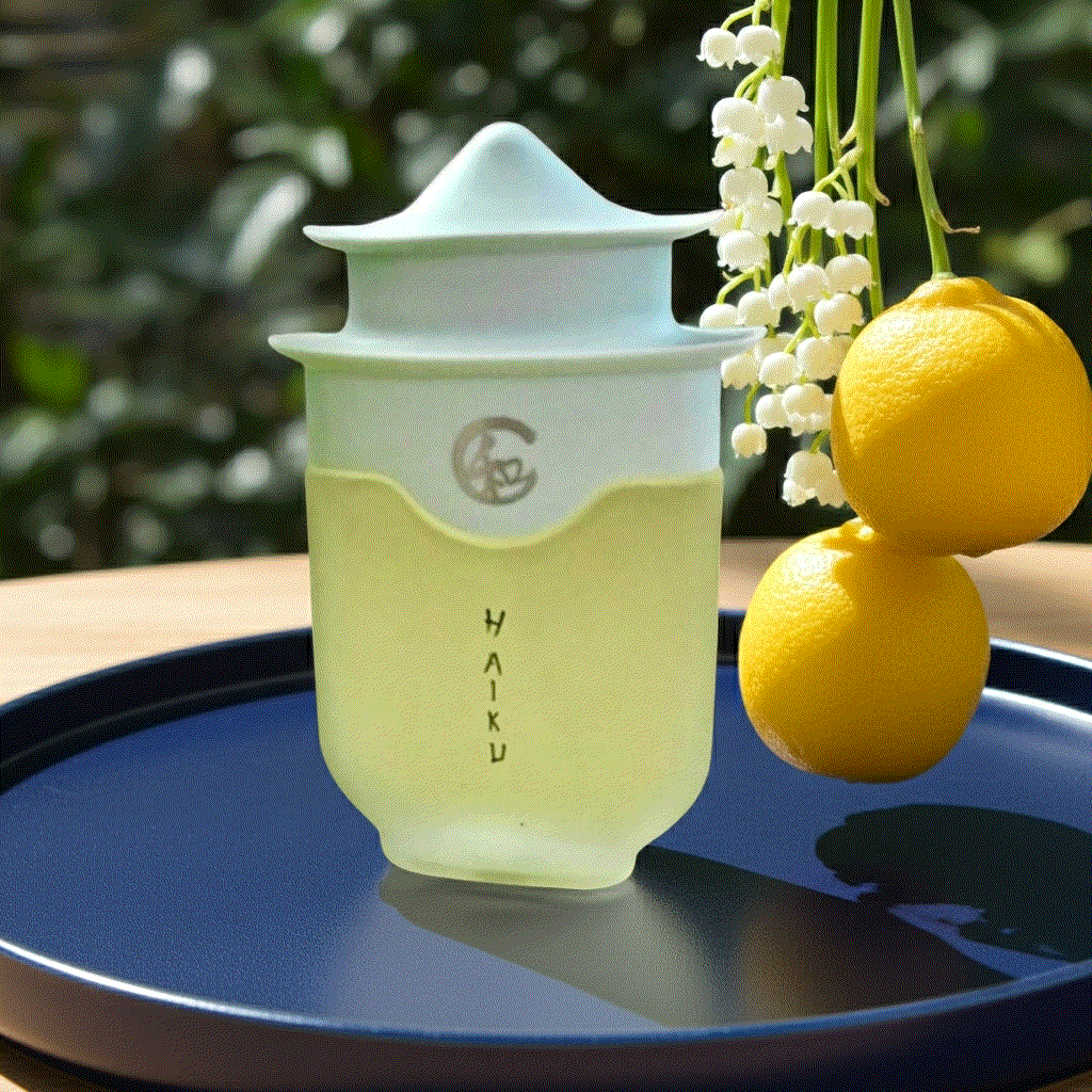Avon Haiku Original Eau De Perfume bottle beside yellow yuzus on tray representing airy floral scent