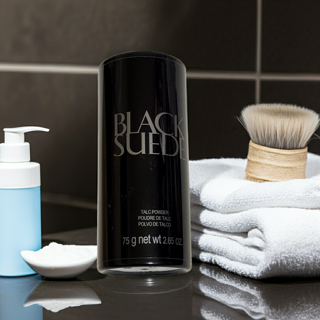 Black Suede talc powder 2.65 oz container on bathroom counter with towels and brush