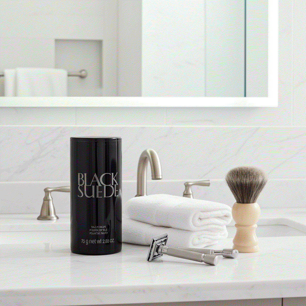 Black Suede talc powder 2.65 oz container on bathroom counter with shaving brush and razor